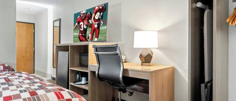 A hotel room with a bed, a desk with a chair, a television, and a wardrobe.