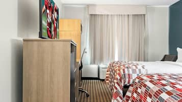 A hotel room with a bed, a desk, a chair, a wardrobe, and a window with curtains.