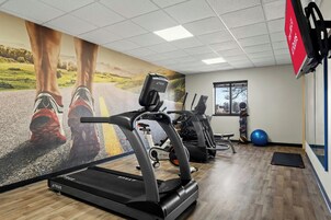 Un gimnasio con cintas de correr, bicicletas estáticas y pelotas de ejercicio.