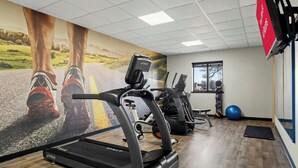 Un gimnasio con cintas de correr, bicicletas estáticas y pelotas de ejercicio.