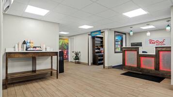 Un área de recepción con un escritorio de madera, un refrigerador, una estación de café y el letrero de Red Roof Inn.