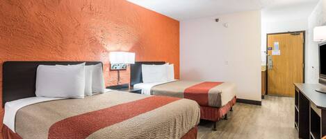 A hotel room with two beds, a TV, a desk, and a door.