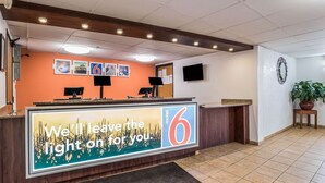 A hotel reception area with a large sign reading "We'll leave the light on for you." and a number "6" on the wall. - Motel 6 Elk Grove Village, IL (Elk Grove Village)