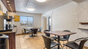 A cafe with a table and chairs, a coffee machine, and a view of the sea through the window. - Motel 6 Elk Grove Village, IL (Elk Grove Village)