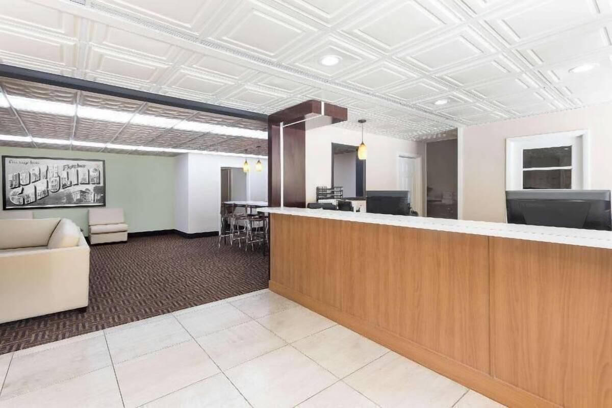 A modern reception area with a wooden counter, a white ceiling, and a framed picture on the wall.