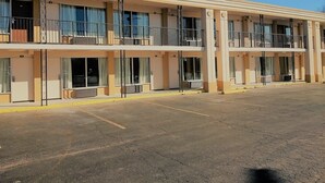 Un motel de varios pisos con balcones, ventanas amplias y un estacionamiento.