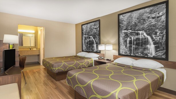 Habitación de hotel con dos camas, televisión, escritorio y espejo de baño.