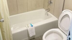 A bathroom with a bathtub, toilet, and a towel rack. - ASHEVILLE AIRPORT INN (Fletcher)
