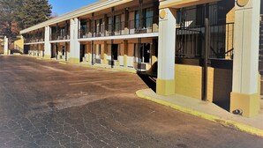A multi-story motel with a row of rooms, a parking lot, and a clear sky. - ASHEVILLE AIRPORT INN (Fletcher)