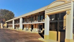 Un motel con varias habitaciones, acceso vehicular y estacionamiento.