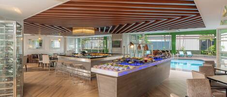 A modern bar area with a pool, wooden flooring, and a glass enclosure with wine glasses.