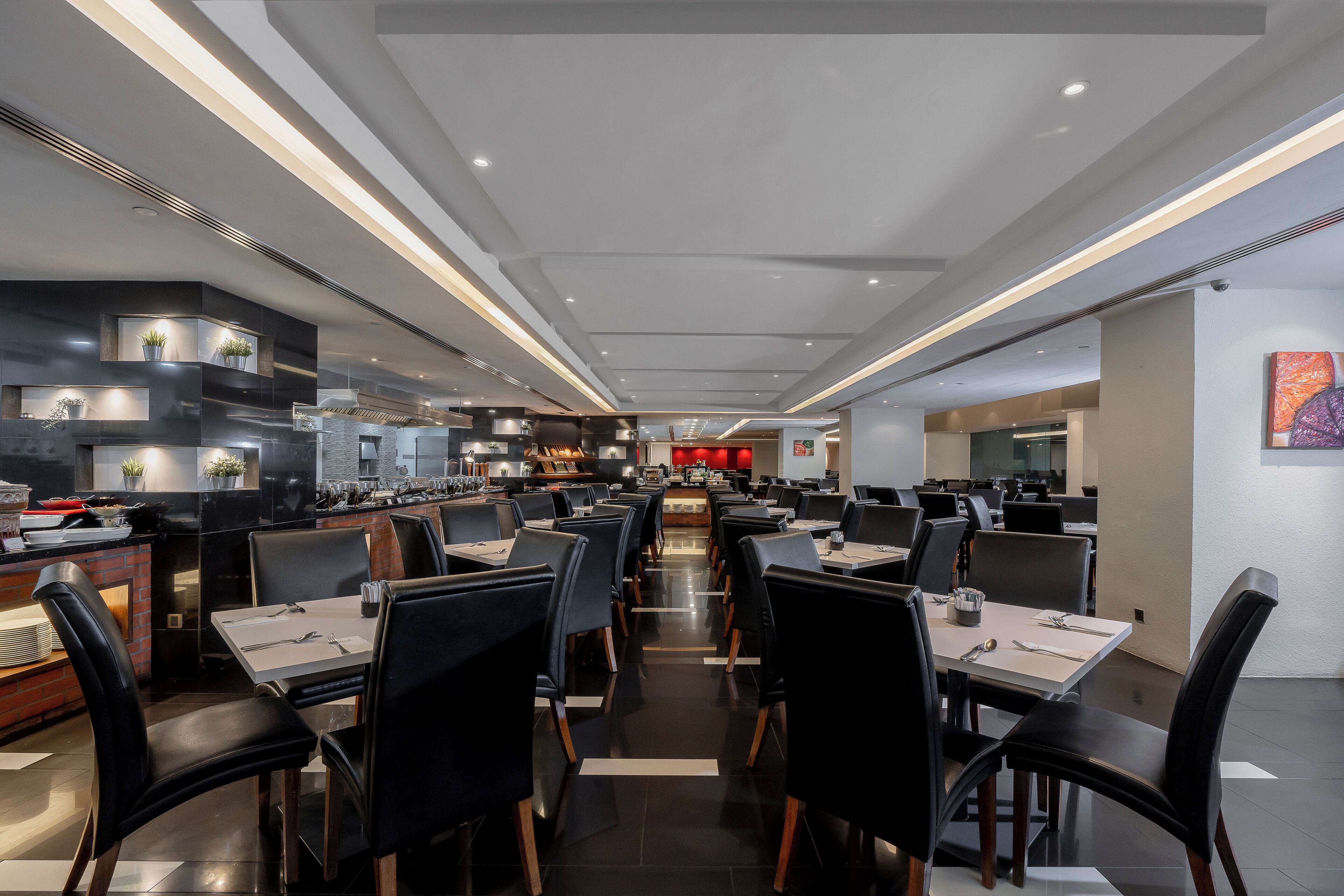 Un restaurant moderne avec un long comptoir, des chaises noires et un espace de restauration central.