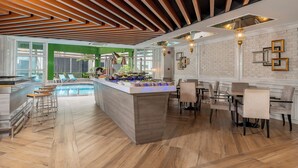 A modern hotel lobby with a pool, bar area, and dining space. - Melia Kuala Lumpur (Kuala Lumpur)