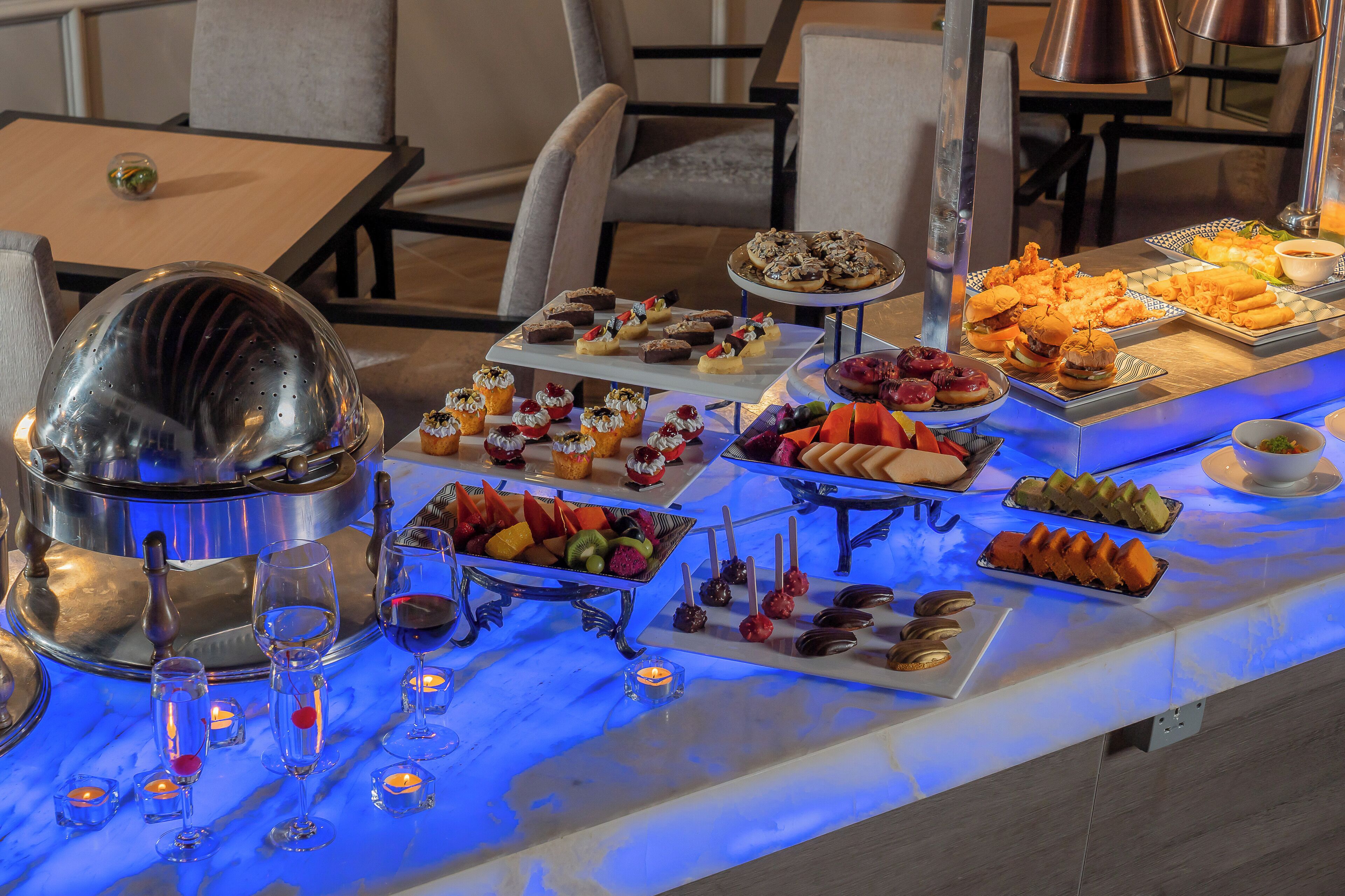 A buffet table with various food items and a large metal pot.