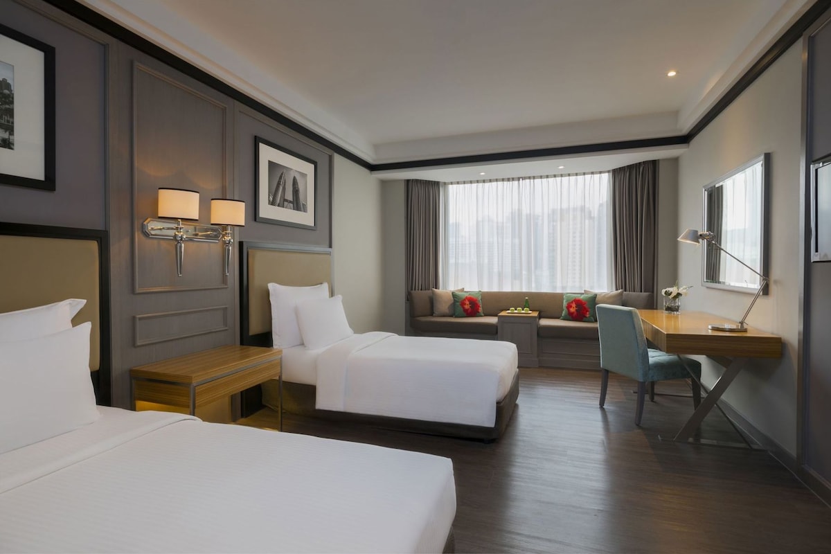 A hotel room with two beds, a desk, and a window with curtains.