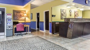 A reception area with a desk, chair, ATM, and a clock on the wall.
