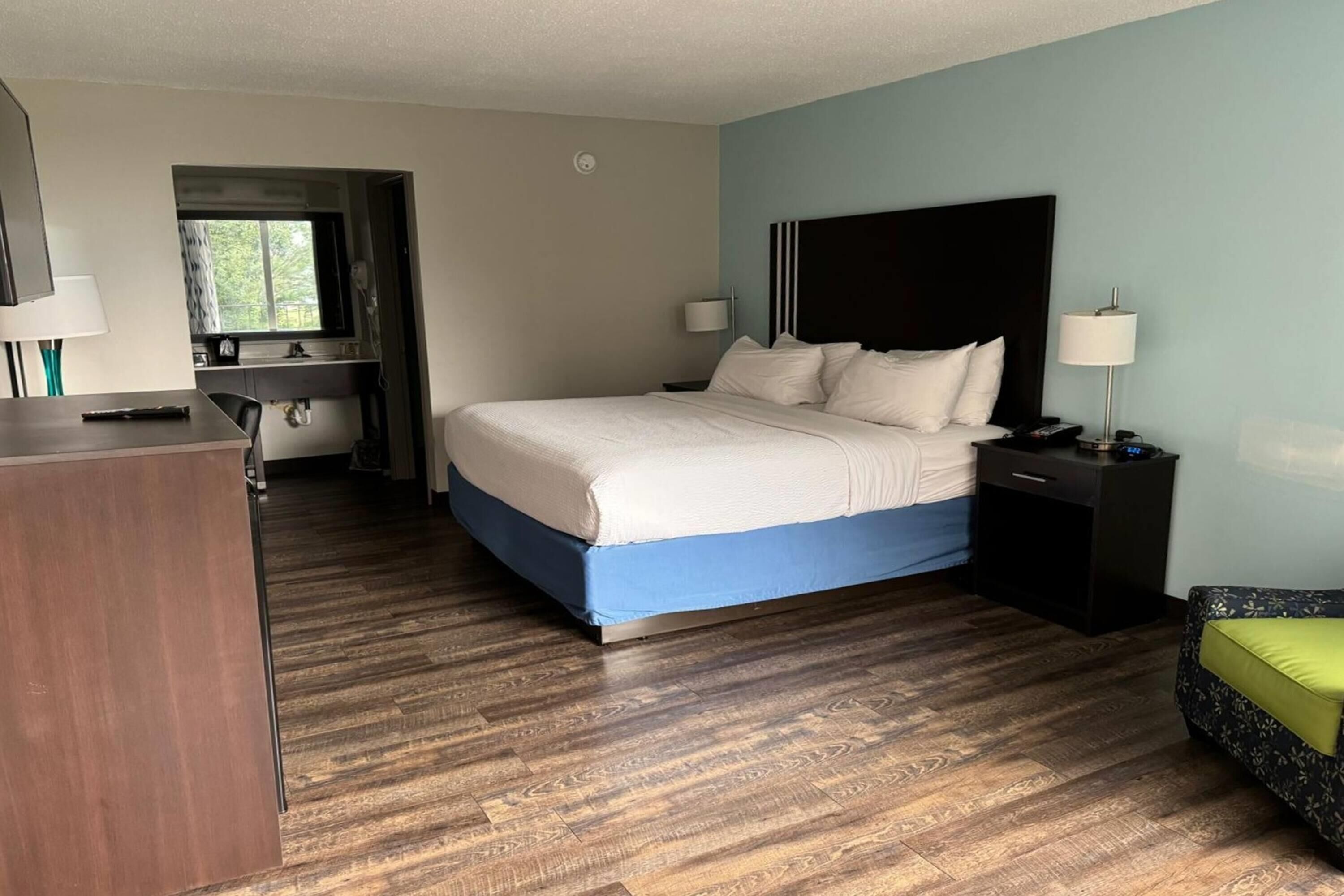 Une chambre d’hôtel avec un lit, des tables de chevet, un bureau et une fenêtre.
