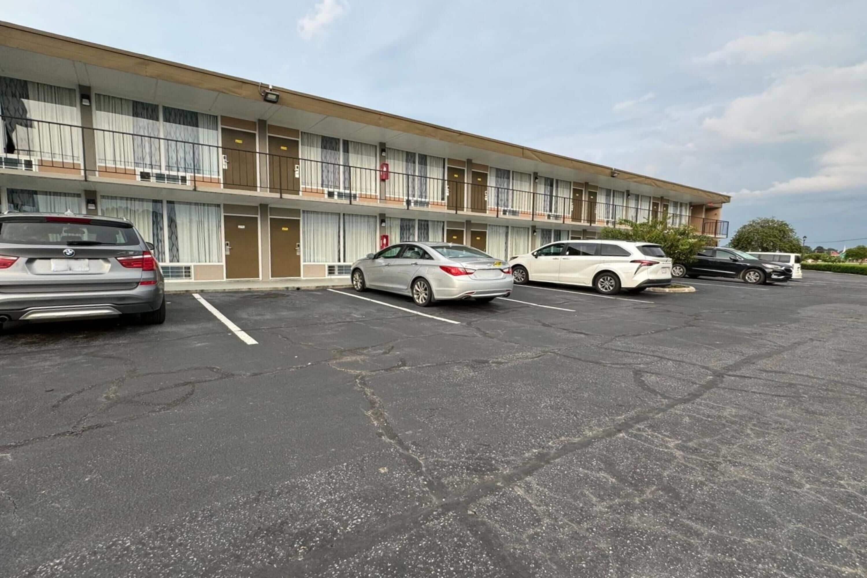 A motel with a row of parking spaces, a building with multiple floors, and a clear sky.