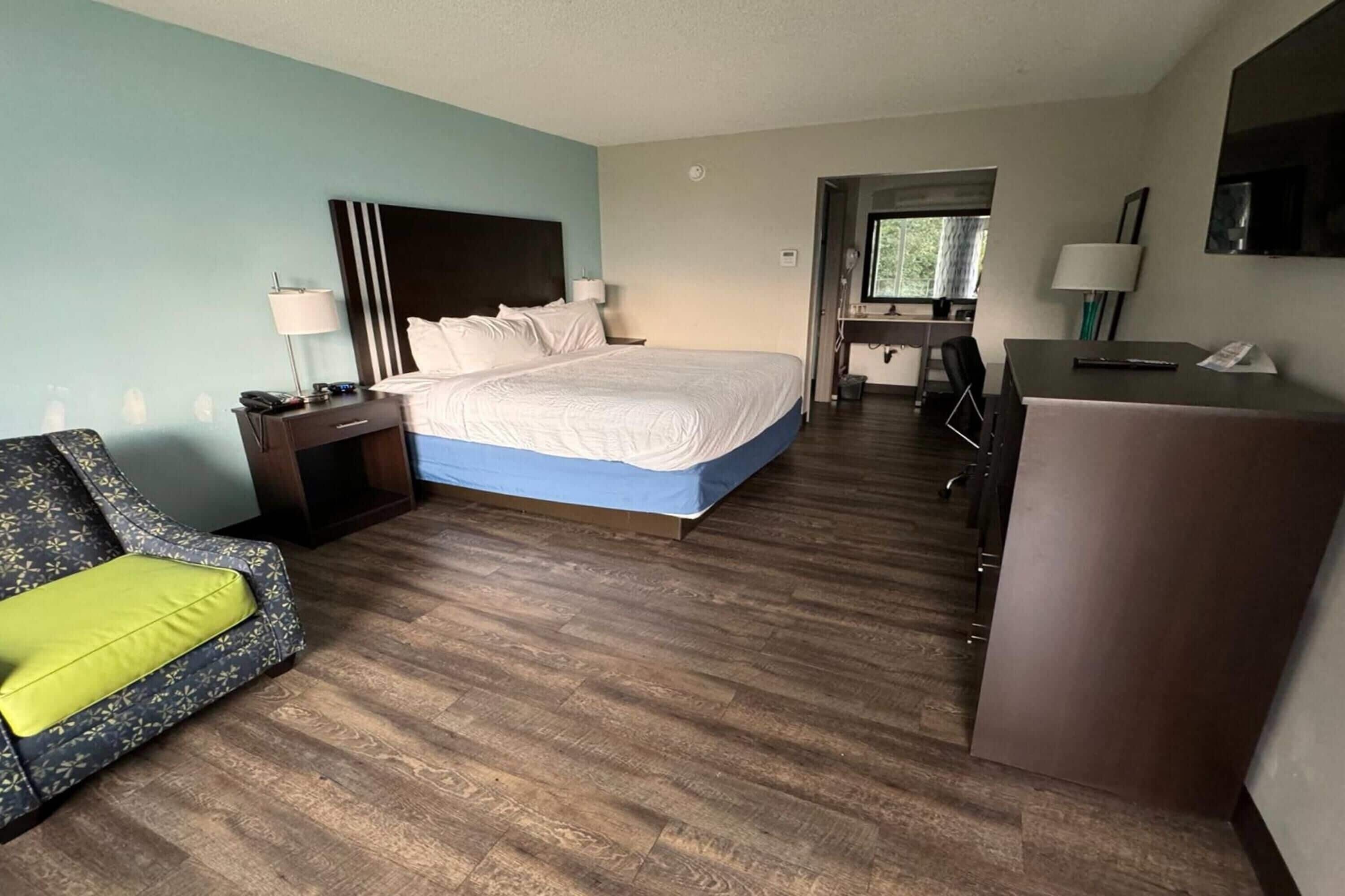 A hotel room with a bed, a desk, a chair, and a TV.