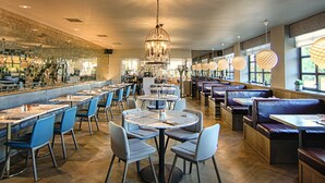 A restaurant with multiple seating areas, including round tables and booths, and a bar area with a mirrored wall. - Strathaven Hotel (Strathaven)