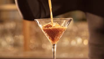 A bartender pouring a drink into a martini glass.