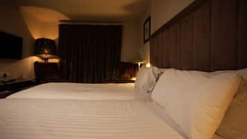 A hotel room with a large bed, a wooden headboard, and a nightstand with a lamp.