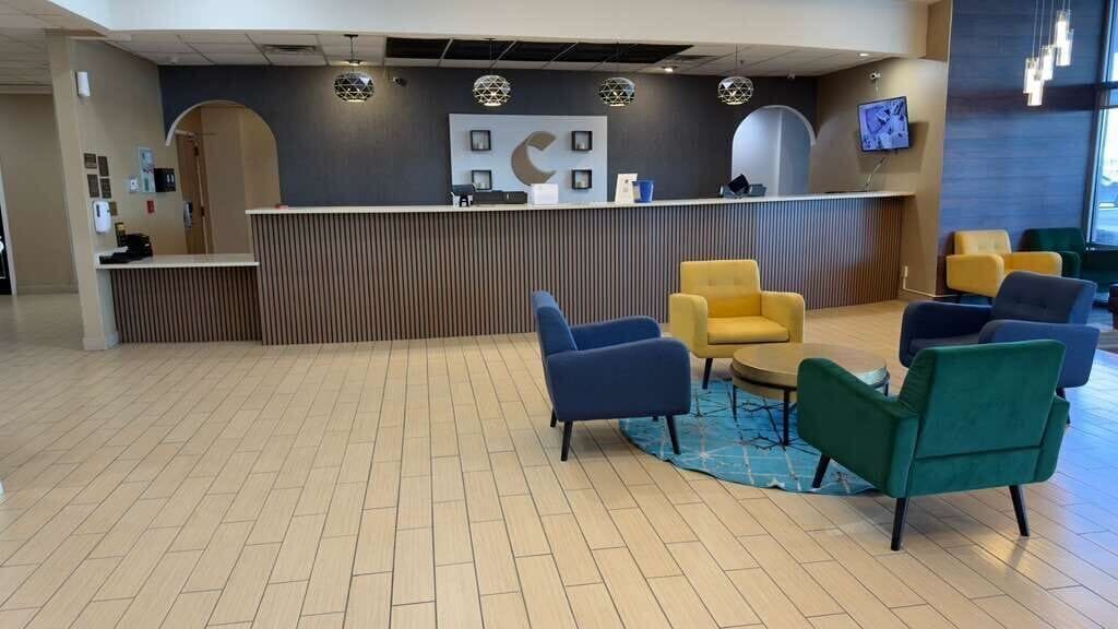 A reception area with a counter, several chairs, and a television screen.