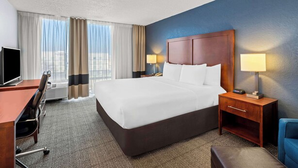 A hotel room with a large bed, a desk with a chair, a TV, and two bedside lamps. - Comfort Inn & Suites Omaha Central (Omaha)