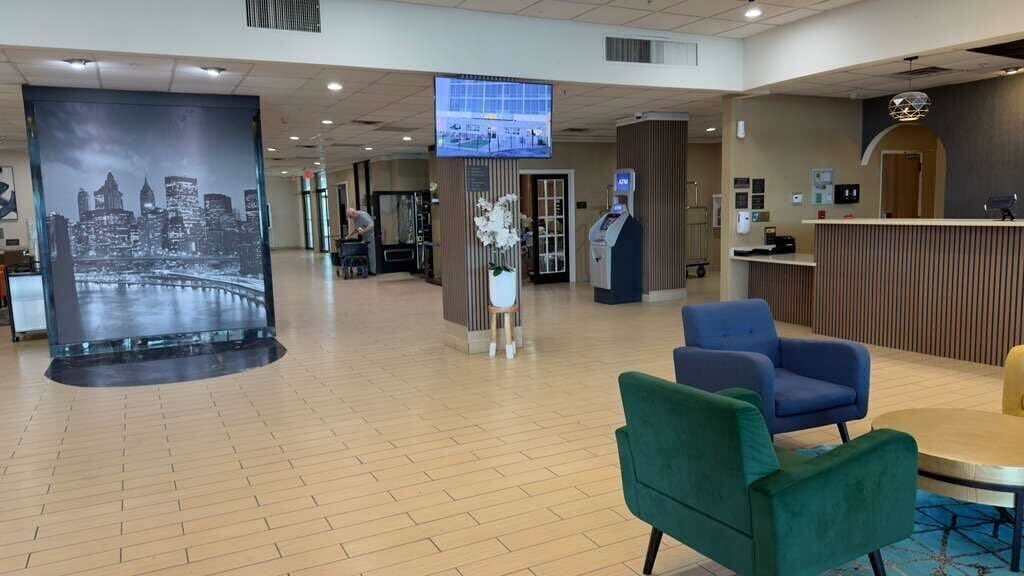 A hotel lobby with a large cityscape mural, a reception desk, and seating areas.
