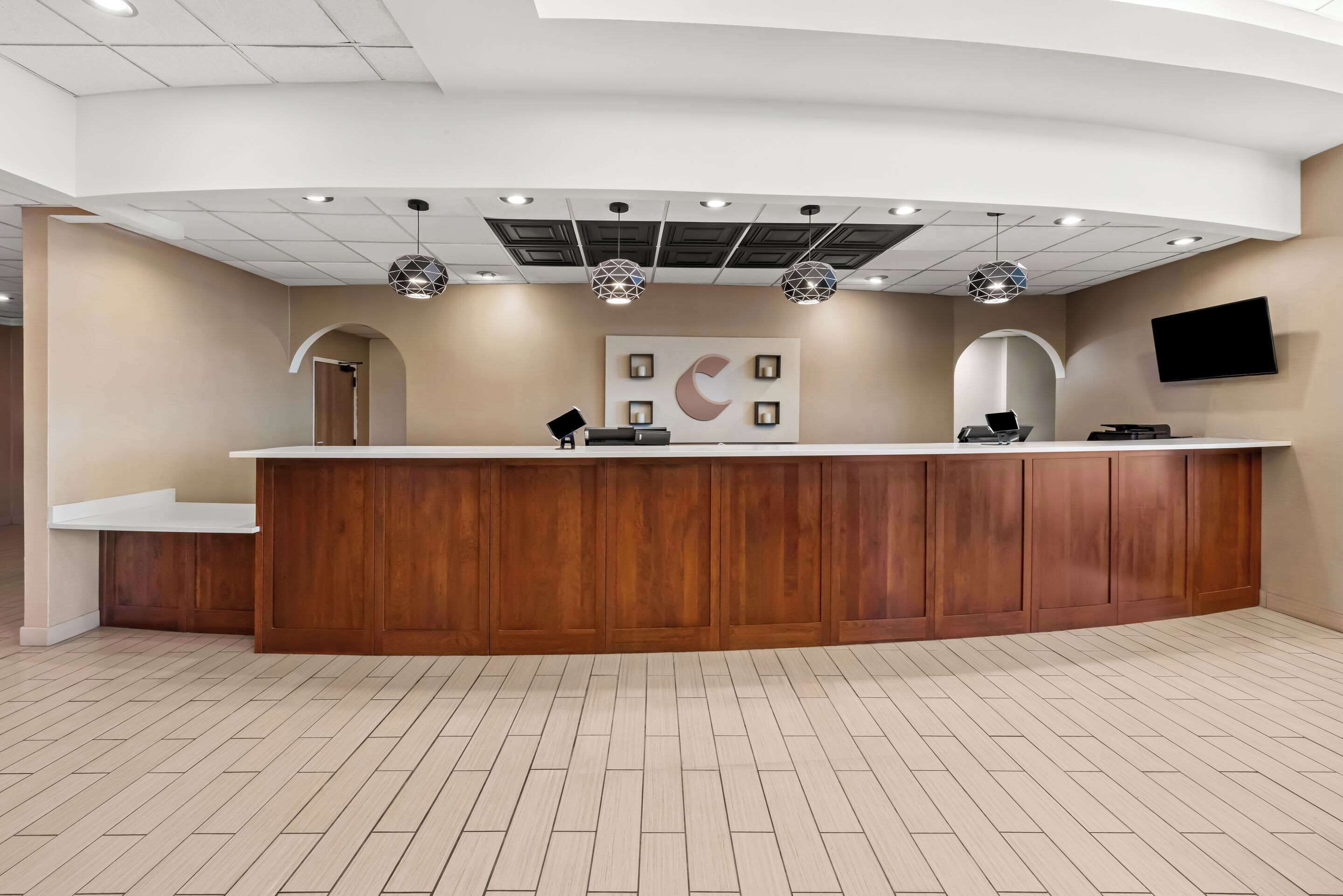 A reception area with a wooden counter, a crescent moon decoration, and a flat-screen TV mounted on the wall.