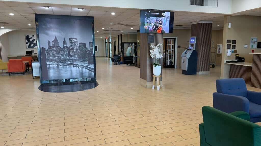 A spacious lobby with a large cityscape mural, an ATM, and seating areas.