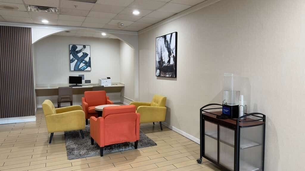 A conference room with a round table, four chairs, a coffee machine, and a water dispenser.