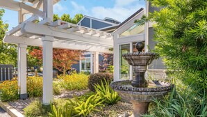 A garden with a stone fountain, white pergola, and various plants. - UpValley Inn & Hot Springs Napa Valley, an Ascend Collection Hotel (Calistoga)