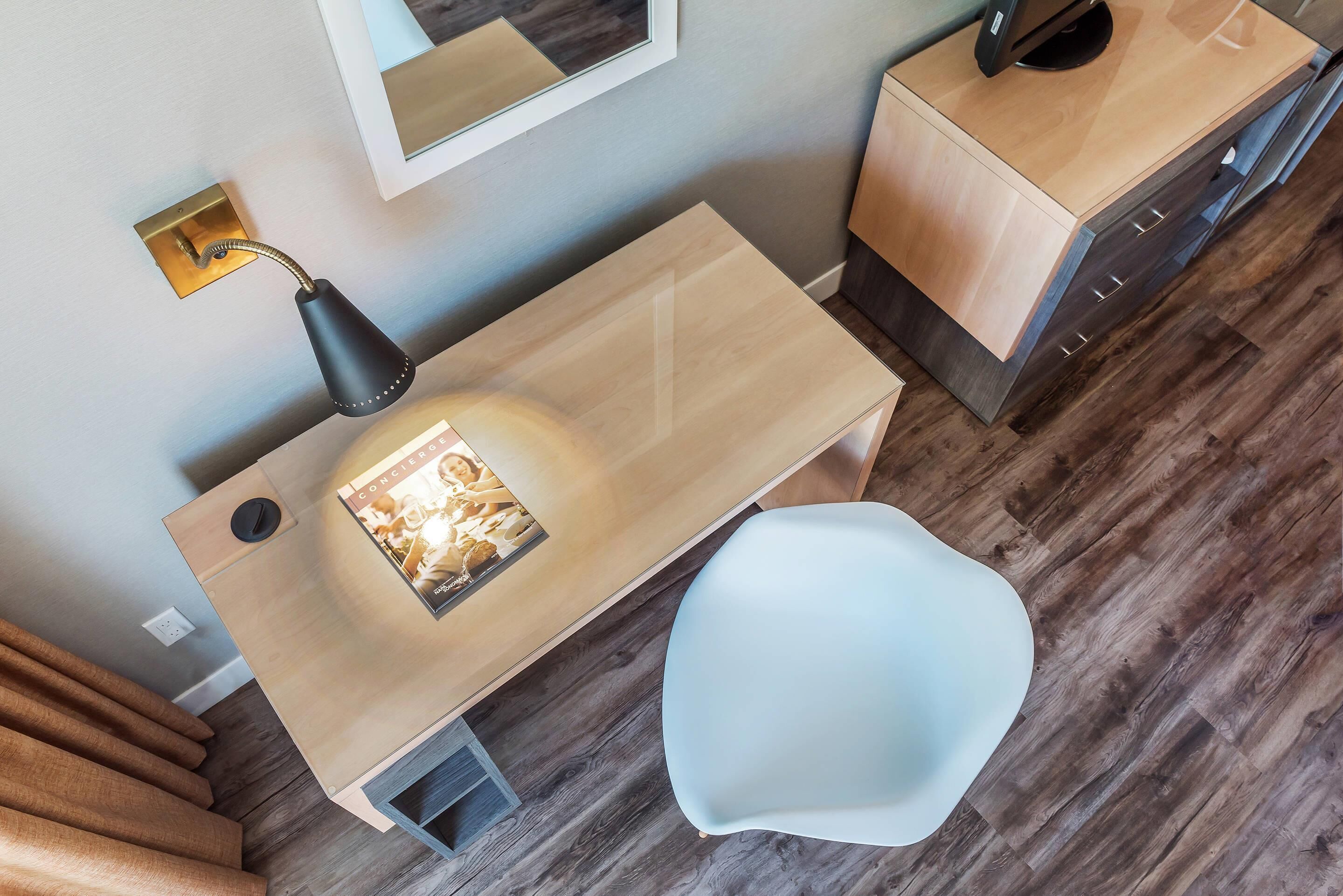 Ein modernes Badezimmer mit einem hölzernen Waschtisch, einem weißen Stuhl und einem Spiegel an der Wand.