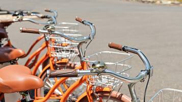 Una fila di biciclette con cestini e selle in pelle, parcheggiate su una superficie pavimentata.
