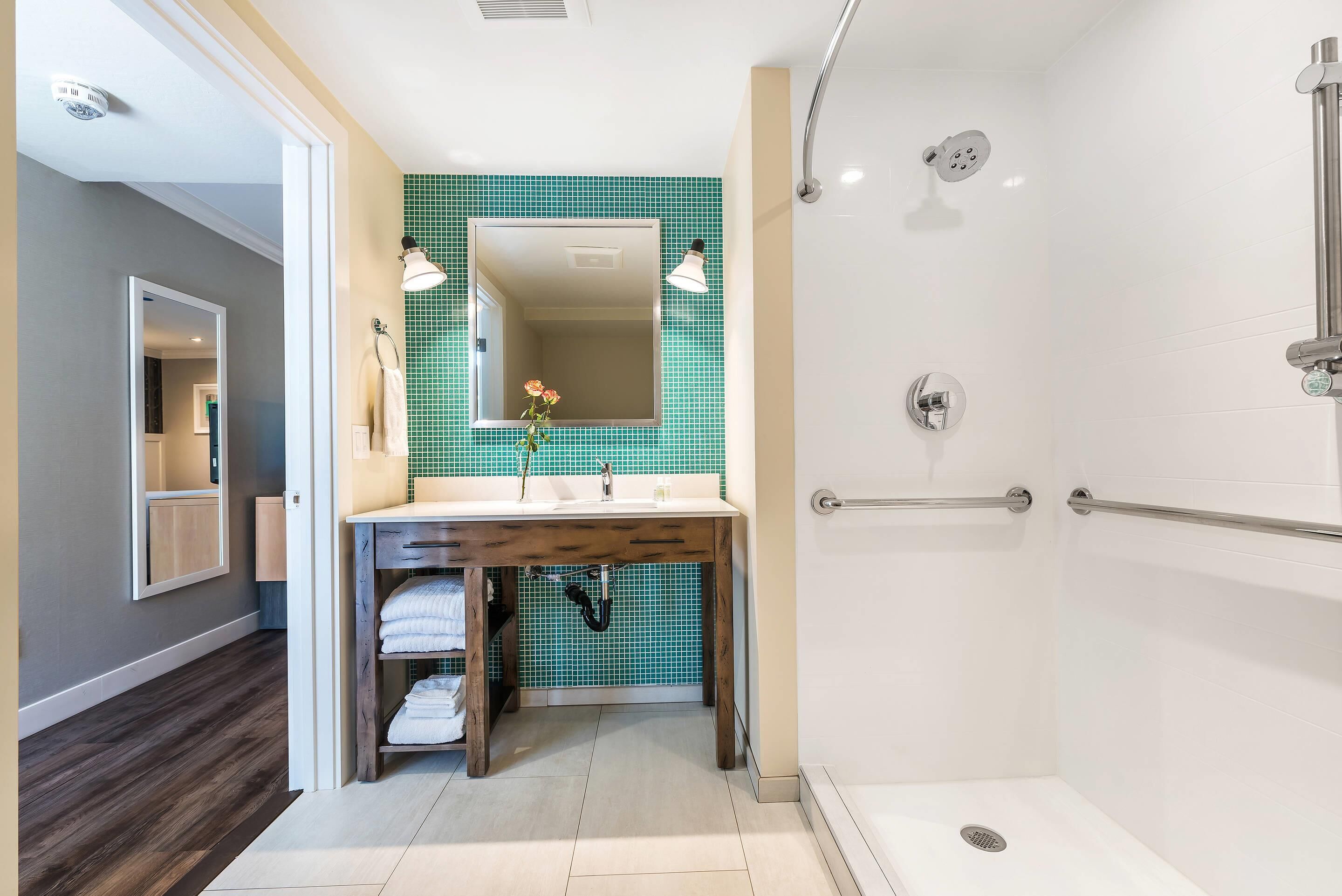 A modern bathroom with a shower, a sink with a mirror, and a towel rack.