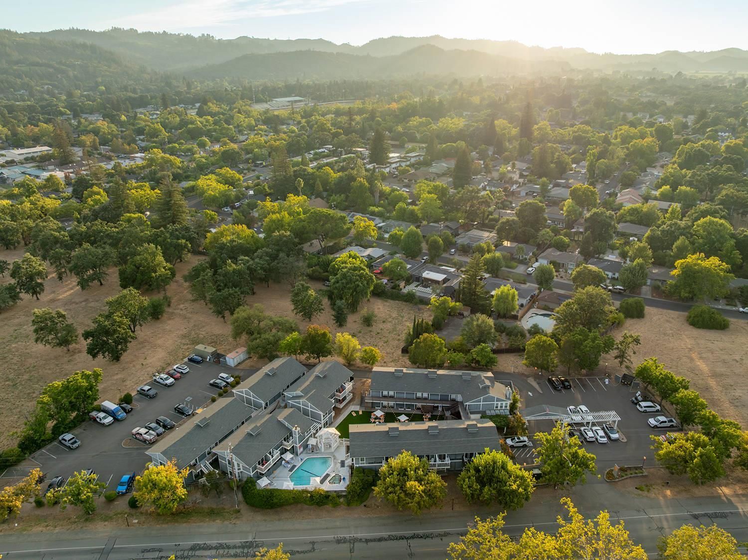 An aerial view of a residential area with houses, a swimming pool, and a parking lot.