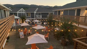 An outdoor patio area with orange chairs and white umbrellas, surrounded by string lights and a wooden fence. - UpValley Inn & Hot Springs Napa Valley, an Ascend Collection Hotel (Calistoga)