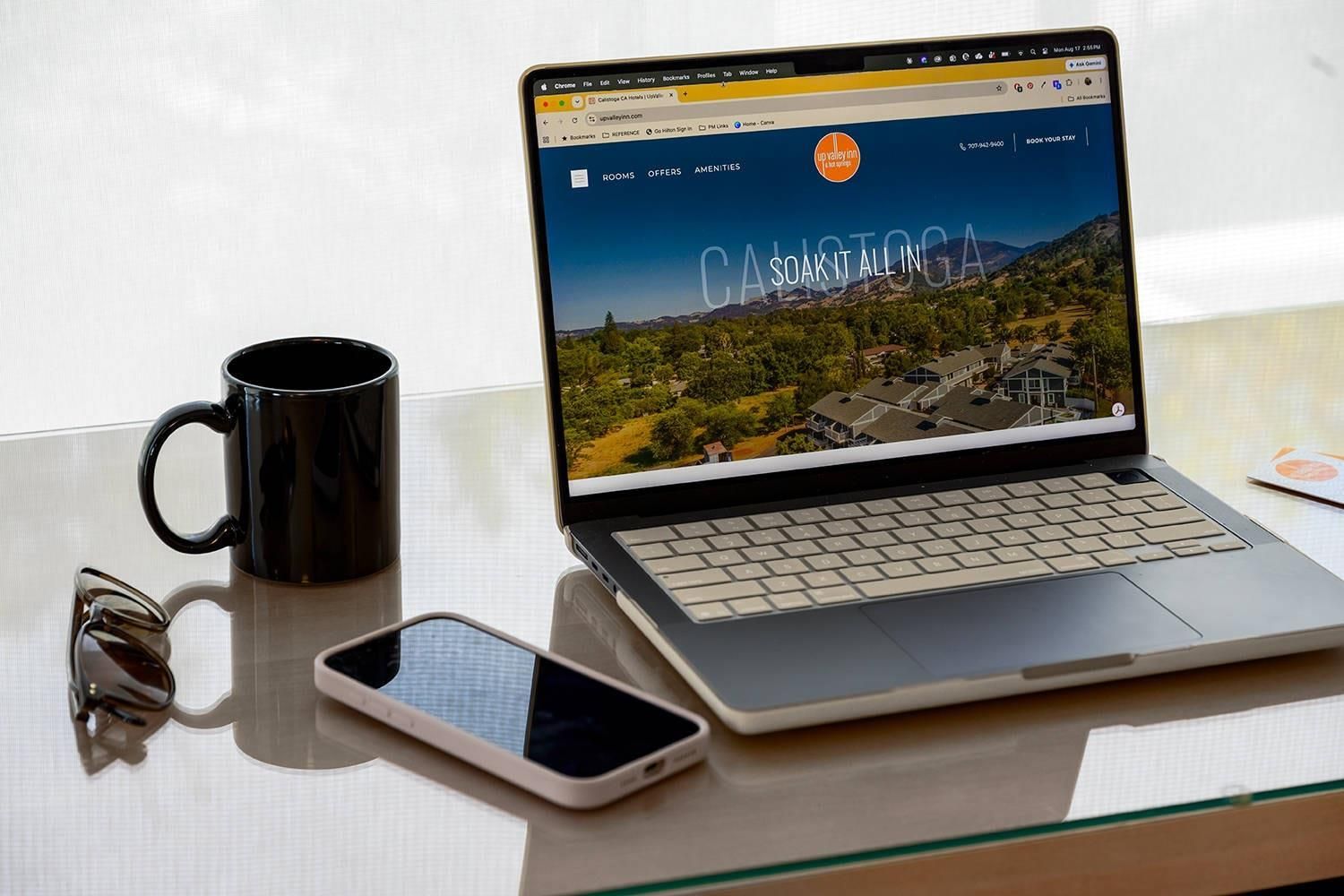 Un ordinateur portable affichant le site web d’un hôtel, avec une vue panoramique sur une région montagneuse.