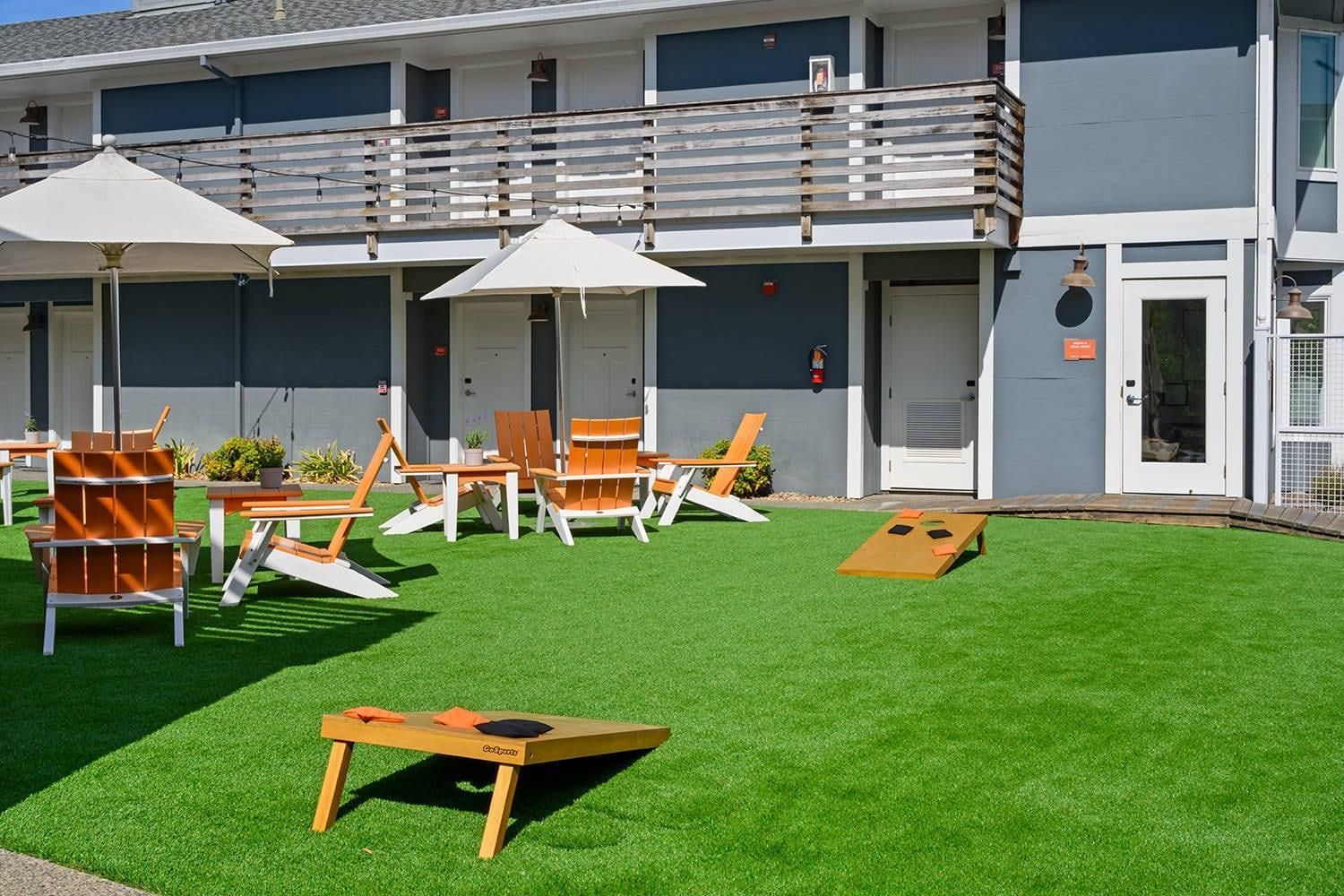 A hotel with outdoor seating, a pool table, and a well-maintained lawn.