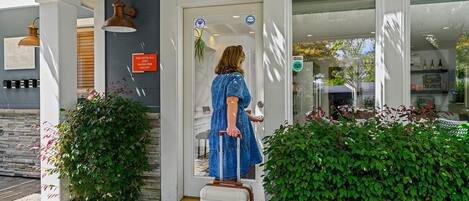 A woman in a blue dress exiting a hotel with a suitcase, a sign indicating the hotel is smoke-free, and a bike symbol suggesting bike parking.