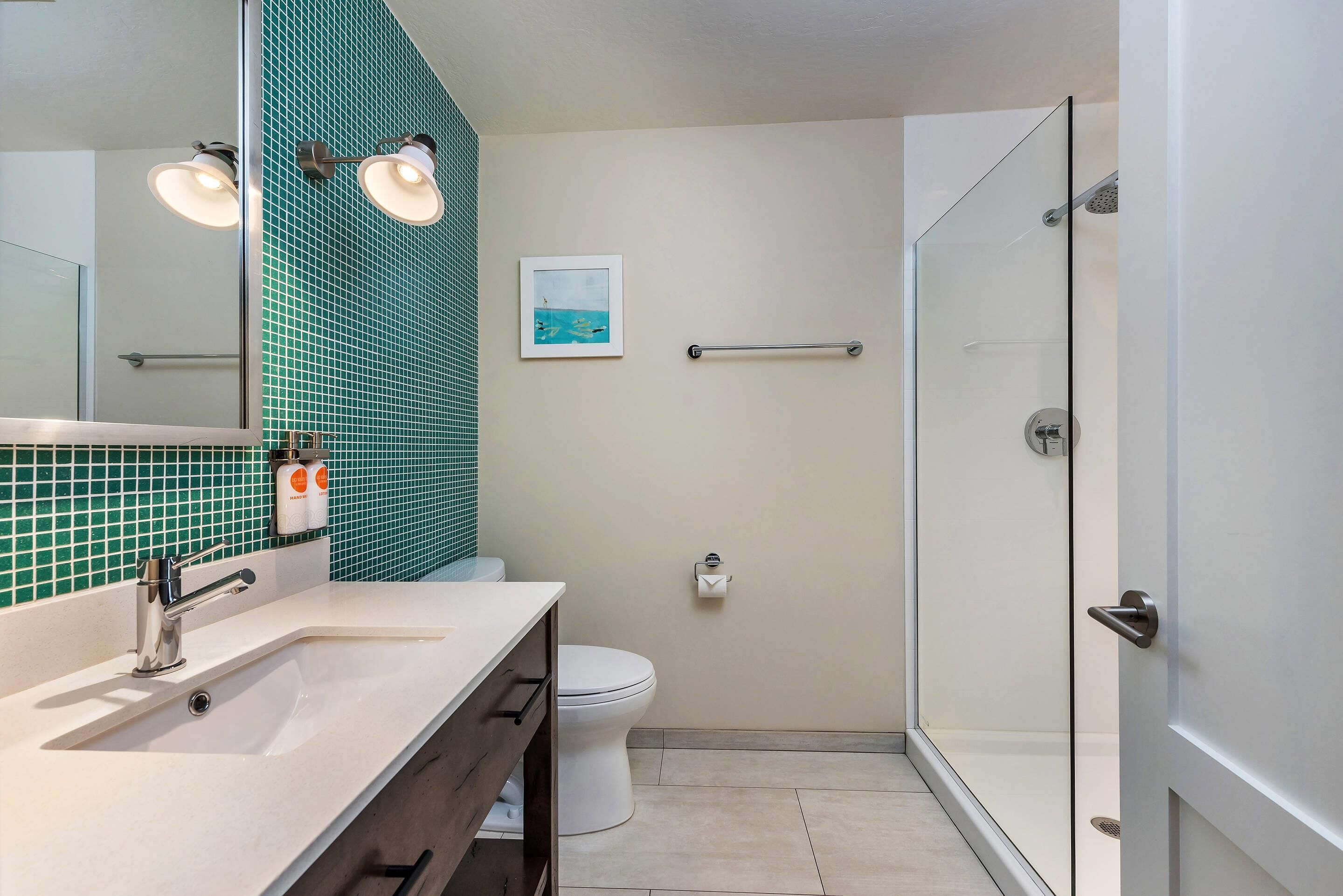 A modern bathroom with a white sink, a glass shower enclosure, and a tiled backsplash.