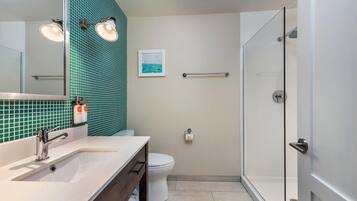 A modern bathroom with a white sink, a glass shower enclosure, and a tiled backsplash.