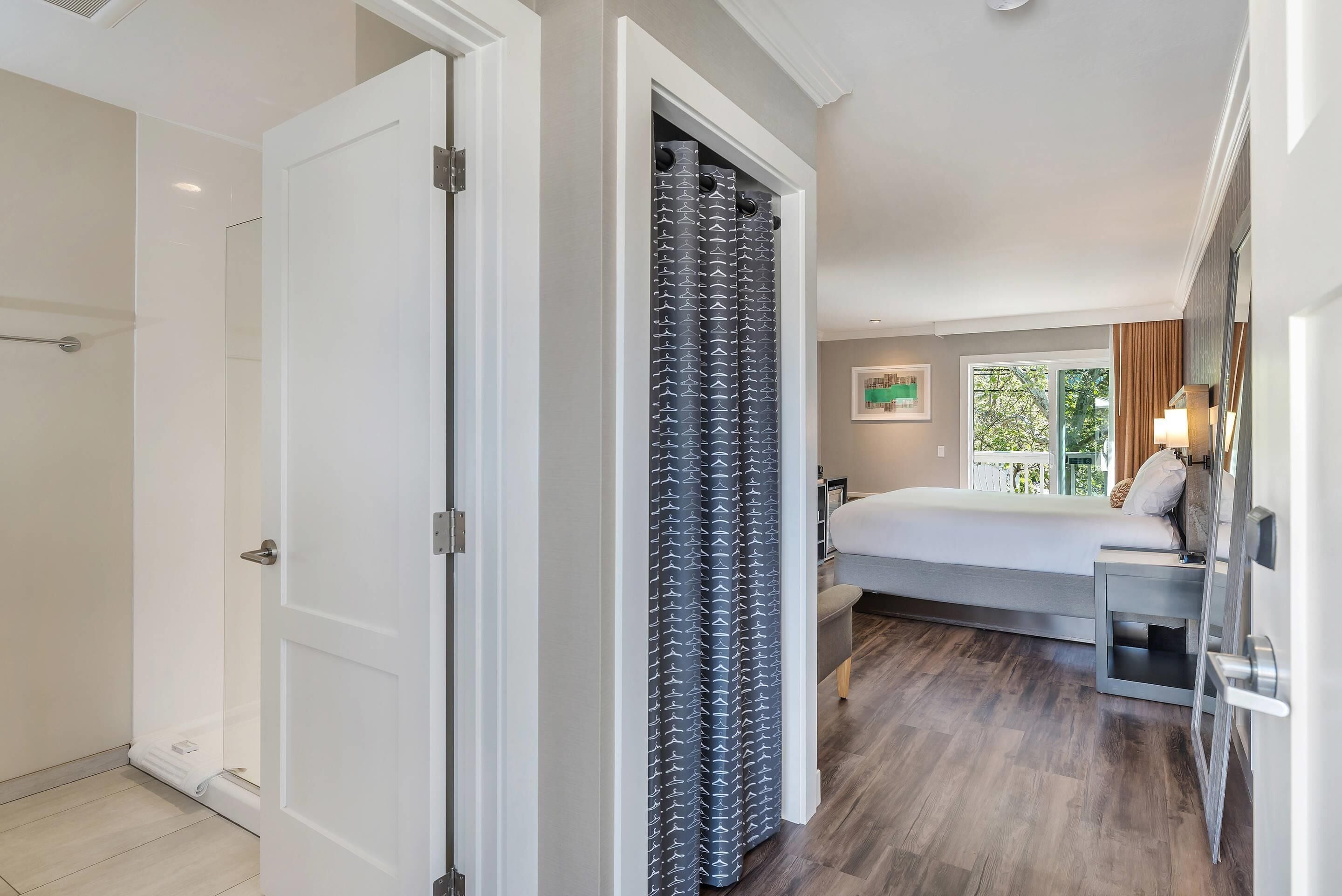 Une chambre d’hôtel comprenant un lit, une table de chevet, une fenêtre avec vue et un espace douche.