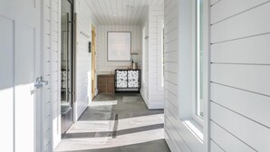 A hallway with white paneling, a vent, a cabinet with a floral pattern, and a sign that reads "soak it all in." - UpValley Inn & Hot Springs Napa Valley, an Ascend Collection Hotel (Calistoga)