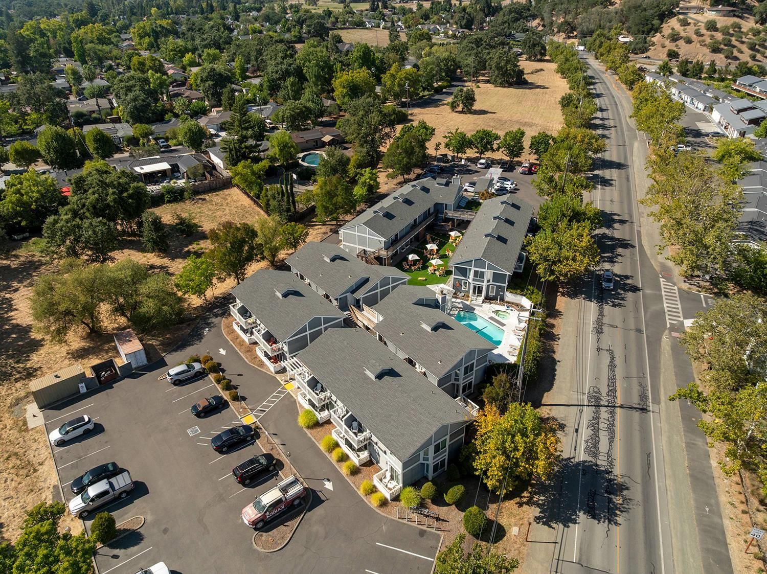 An aerial view of a residential area with a row of houses, a parking lot, and a swimming pool.
