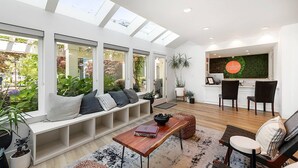 A modern living room with a built-in bench, a dining area with a wooden table, and a kitchen with a green backsplash. - UpValley Inn & Hot Springs Napa Valley, an Ascend Collection Hotel (Calistoga)