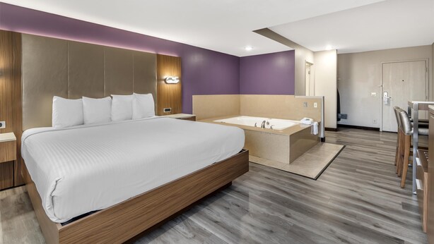 Ein modernes Hotelzimmer mit einem großen Bett, einer separaten Badewanne und einer Sitzecke mit Sesseln.