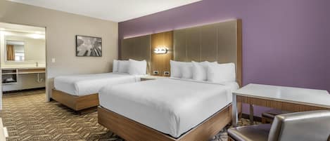 A hotel room with two beds, a desk, a chair, and a large mirror.