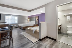 A modern hotel room with a large bed, a separate bathroom with a bathtub, a desk with a chair, and a large window providing natural light. - Best Western Airport Plaza Hotel – LAX  Airport LA Stadium (Inglewood)